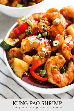 two bowls filled with shrimp and veggies on top of a white table cloth