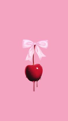 a heart shaped object with a white bow hanging from it's end on a pink background