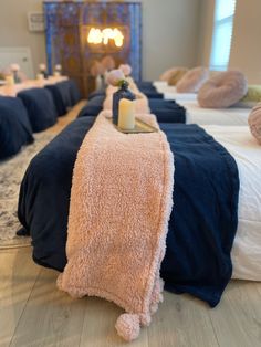 a row of beds covered in blankets with candles on them