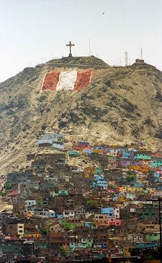 a hill covered in lots of buildings with a cross on top