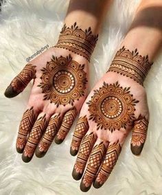 two hands with henna tattoos on them, one is showing the intricate pattern and the other