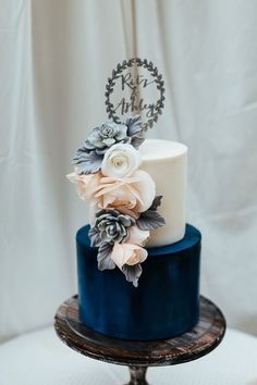 a blue and white wedding cake with succulents