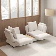 a white couch sitting on top of a wooden floor next to a window in a living room