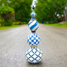 three blue and white vases sitting on top of each other in the middle of an empty road