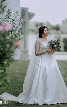 a woman in a wedding dress holding a bouquet and looking off into the distance with her eyes closed