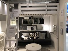 a living room with a loft bed next to a black couch and white table in front of it