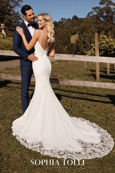 a bride and groom standing in front of a fence