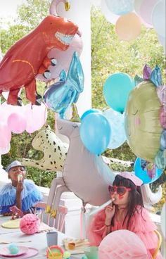 two people sitting at a table with balloons