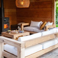 an outdoor living area with couches, table and wood burning stove in the background