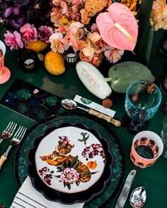 the table is set with plates, silverware and flowers