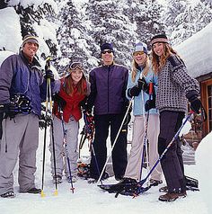 a group of people standing next to each other in the snow with skis on