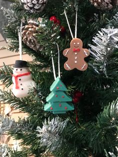 christmas ornaments hanging from a tree with pine cones and snowmen on it's branches