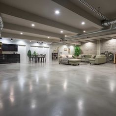 an empty room with couches, chairs and tables in the center is lit by recessed lights