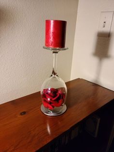 a red candle sitting in a glass vase on top of a wooden table