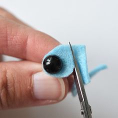 someone is holding a pair of scissors with something blue and black on it's tip