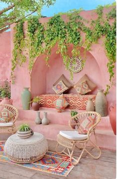 an outdoor area with wicker furniture and potted plants on the wall, along with pink walls