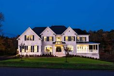 a large white house lit up at night with lights on the front and side windows