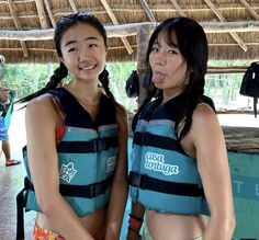 two women in life vests standing next to each other with their mouths open and tongue out