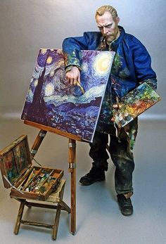 a man standing next to an easel holding a painting on it's side