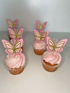 three cupcakes with pink frosting and gold butterflies