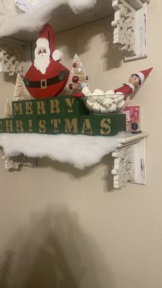 a santa clause sign hanging from the side of a wall next to snow covered shelves