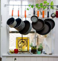 pots and pans are hanging on the window sill