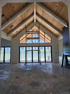 the inside of a building that is being built with wooden beams and glass doors on both sides