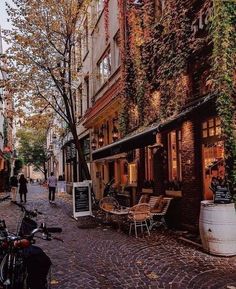 a cobblestone street lined with parked bikes and tables