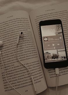 an open book with ear buds and headphones laying on top of it next to an iphone