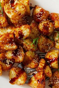 a white plate topped with tofu covered in sesame seeds and garnished with green onions