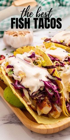 the best fish tacos with cole slaw, lime and mayonnaise on a wooden platter