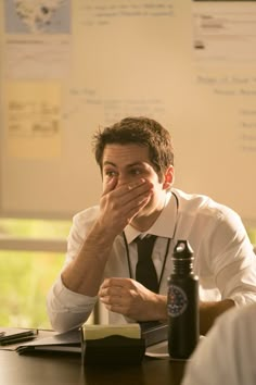 a man covering his face while sitting at a desk