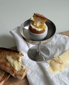 two pieces of bread with an egg in the middle on a plate next to buttered crackers