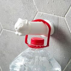 a plastic water bottle with a cat shaped cap on the top, attached to a tile wall