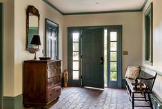 an entryway with a bench, mirror and door to another room in the house