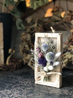 a small wooden box with dried flowers in it