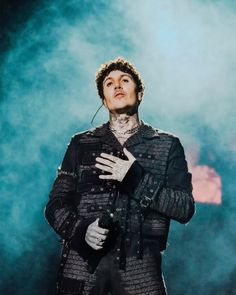 a man in black jacket and white gloves standing on stage with his hands folded over his chest