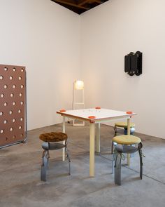 two chairs and a table in an empty room with polka dots on the wall behind them