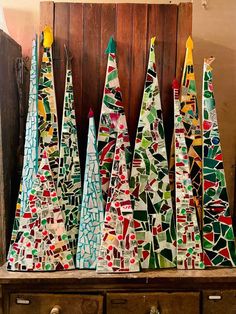 several colorful christmas trees sitting on top of a wooden table