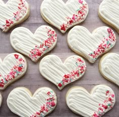 heart shaped cookies with sprinkles and icing on a wooden table top