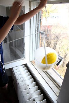 a man is washing his hands in the window sill with a yellow and white bowl