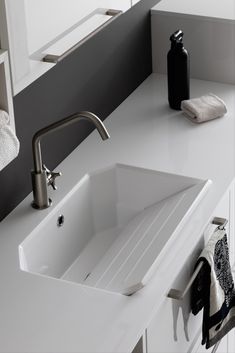 a white sink sitting on top of a counter next to a black bottle and towel