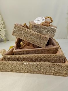 three decorative boxes are stacked on top of each other, one is gold and the other is brown