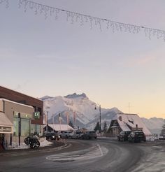 cars parked on the side of a road in front of a snow covered mountain range