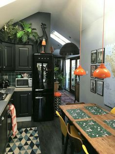 a kitchen with black cabinets and an orange light hanging from the ceiling over the sink