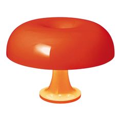 an orange table lamp sitting on top of a white surface