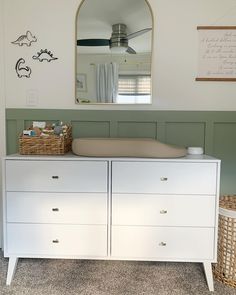 a dresser with a mirror above it and a baby crib in front of it