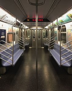 the inside of a subway car with blue seats and metal railings, at night