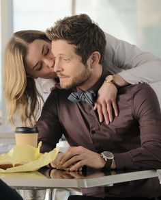 a man and woman sitting at a table kissing