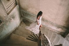 a woman in a white dress is walking down the stairs